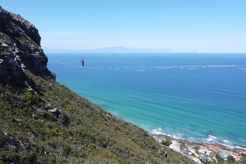 highliner walks on Table Mountain overlooking False Bay in Cape Town, South Africa.