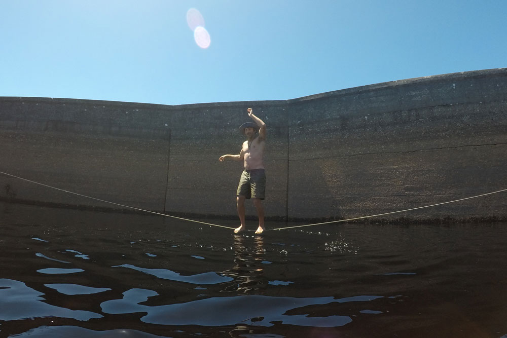 slackliner stands above water in Cape Town's Lewis Gay Dam